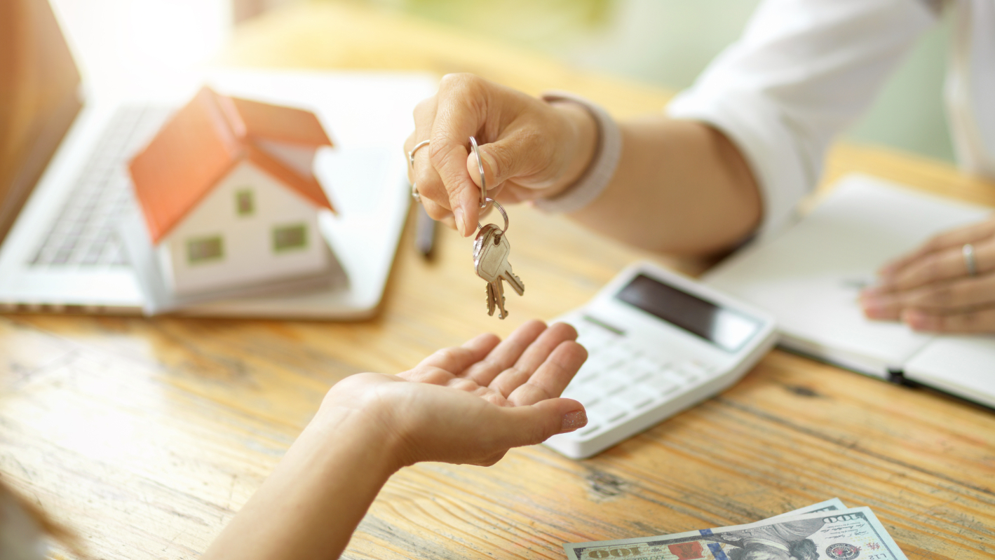 Close-up of a female real estate agent handing over the keys to the new owner of a house